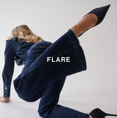 Model kneeling in dark flare jeans and black heels – Flare fit.