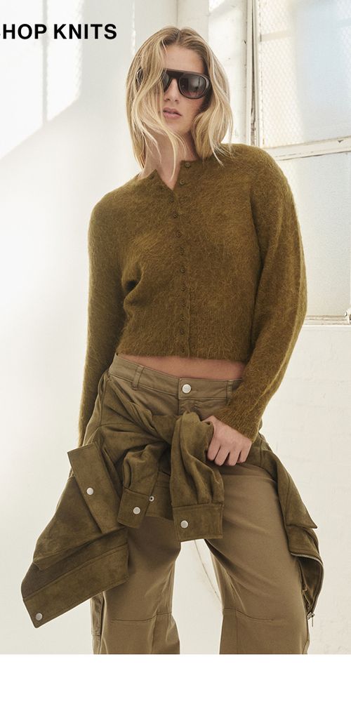 Model posing on a chartreuse knit cardigan. SHOP KNITS.