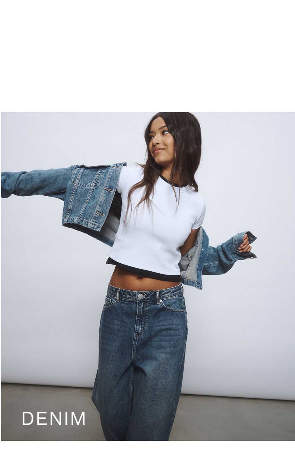 Young girl wearing a denim jacket and denim jeans against a neutral background. SHOP TEEN DENIM.
