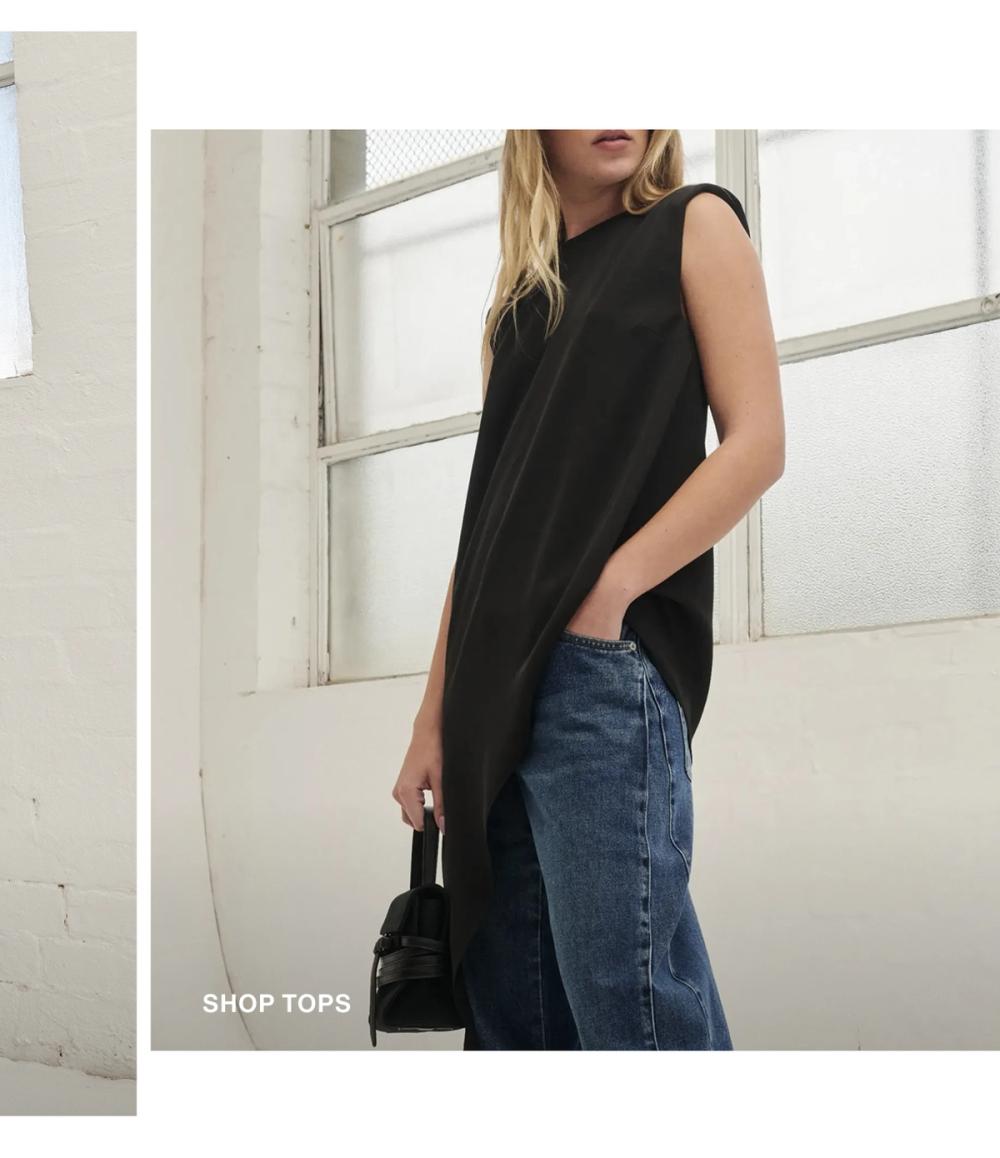 Model posing in a black side drape top. SHOP TOPS.