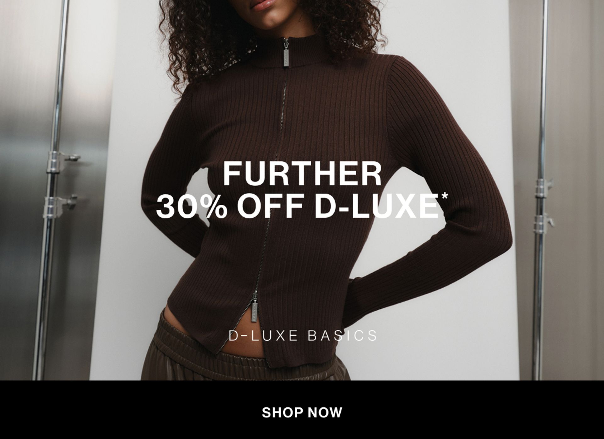 Model wearing a brown zip-up knit in a studio. Text reads FURTHER 30% off D-LUXE.