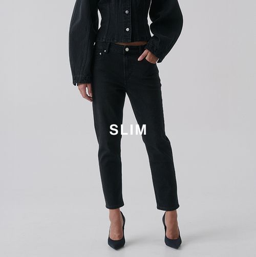 Model wearing slim black jeans and heels – Slim fit.