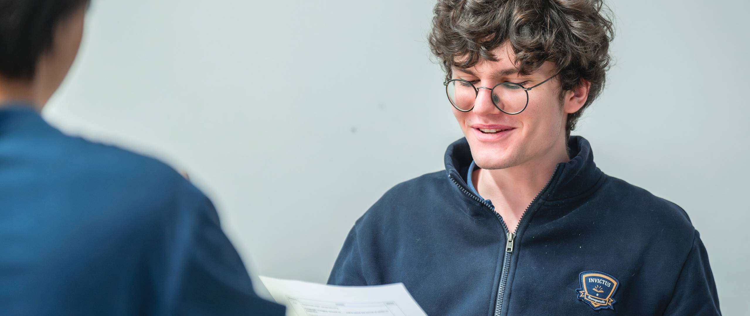 Glass door featuring the Invictus International School logo and branding in blue and gold at the entrance of the Hong Kong campus.