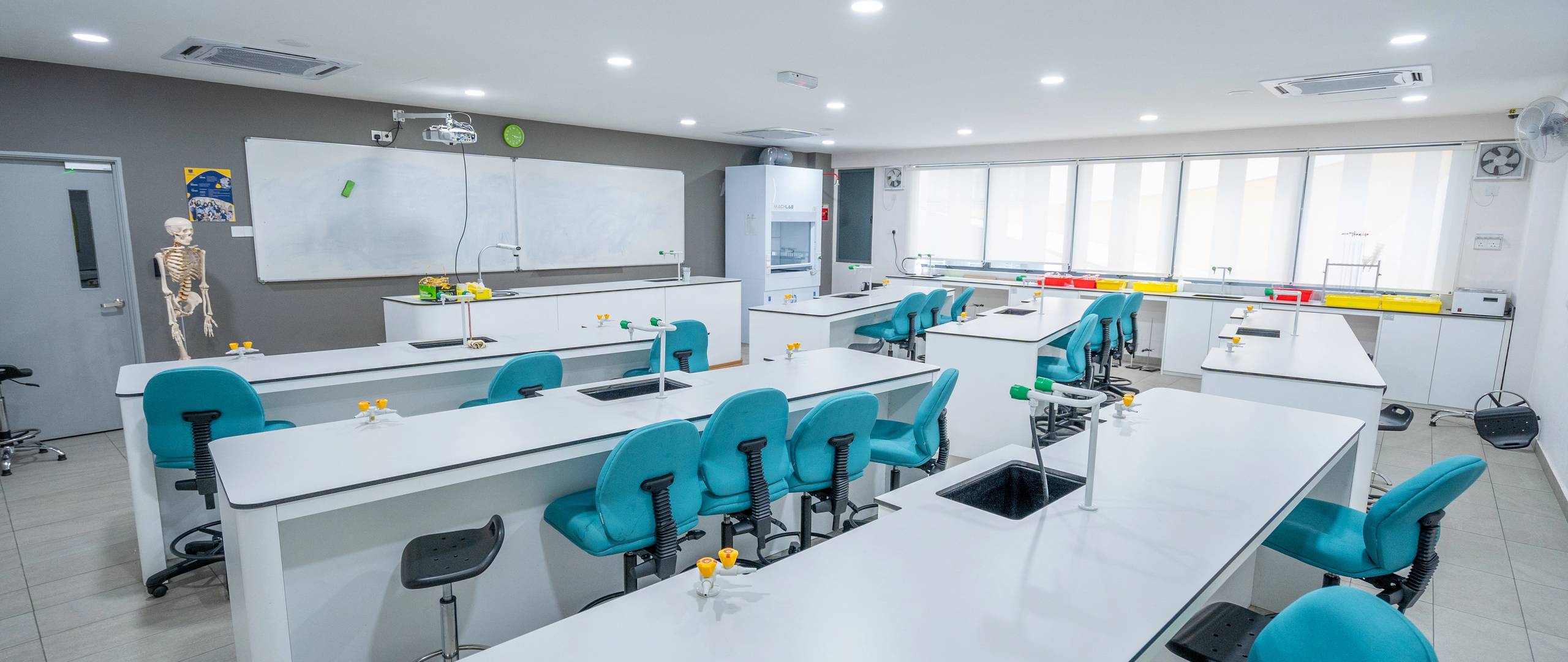 Science lab with white benches, blue chairs, and lab sinks.