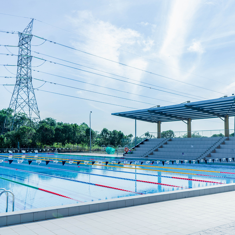 Invictus International School Malaysia Spring Hills Campus outdoor Olympic-size swimming pool with spectator stands and pavilion roof