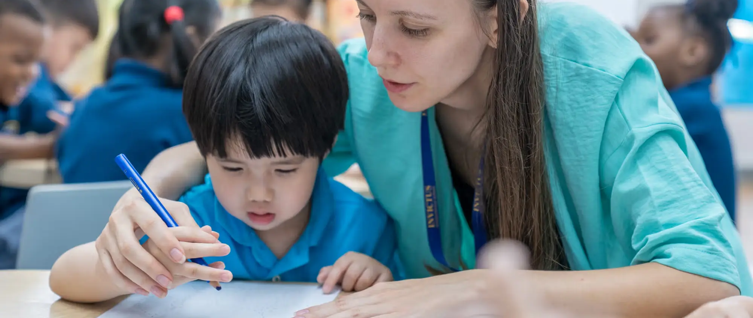 Teacher helping Kindergarten student writing names of colours