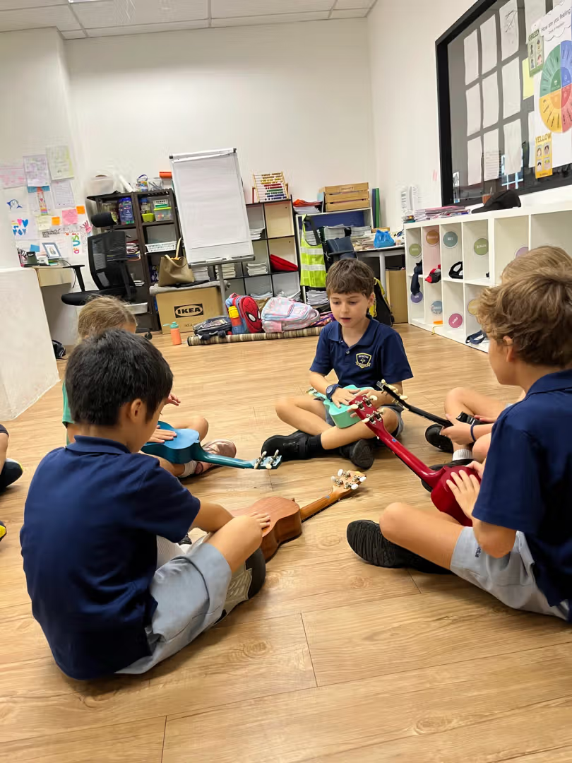 Ukulele class: four kids taking a break holding their multicoloured ukulele