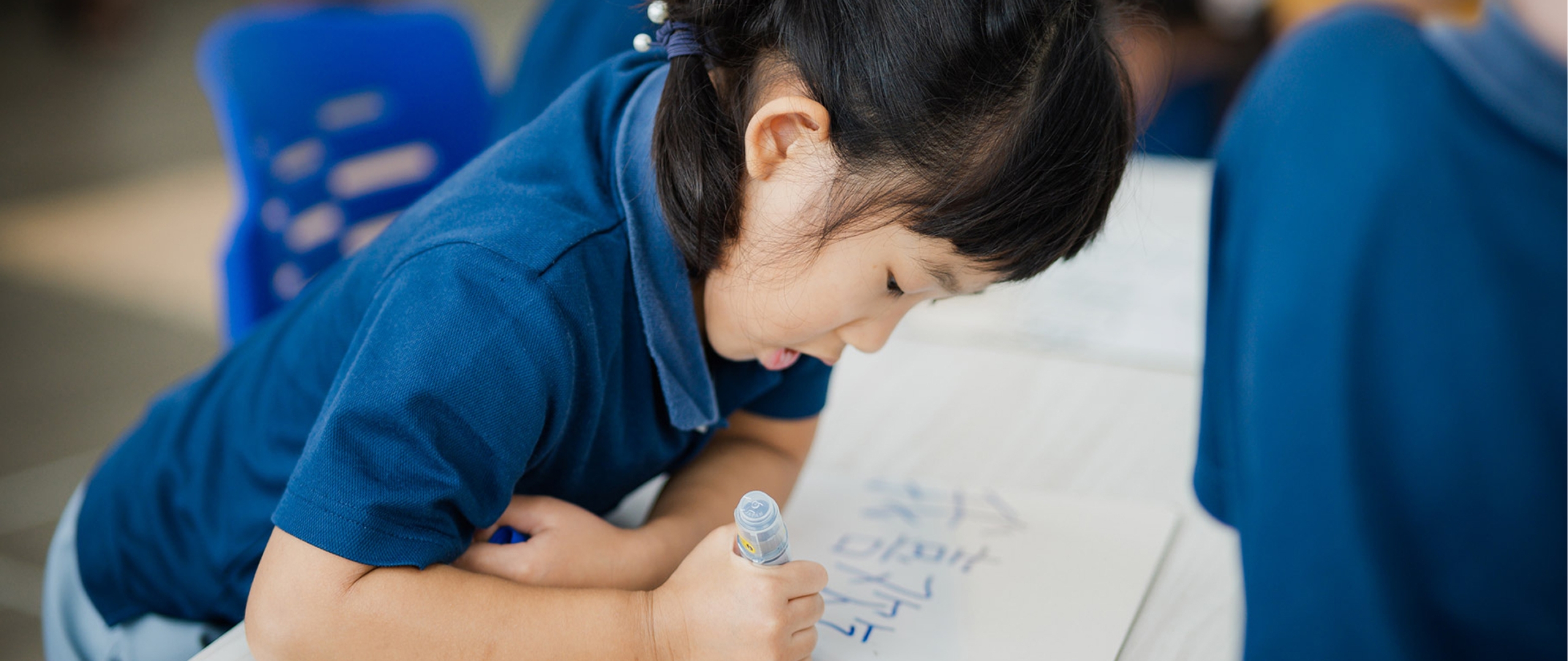 A young student learning to write Mandarin characters in class