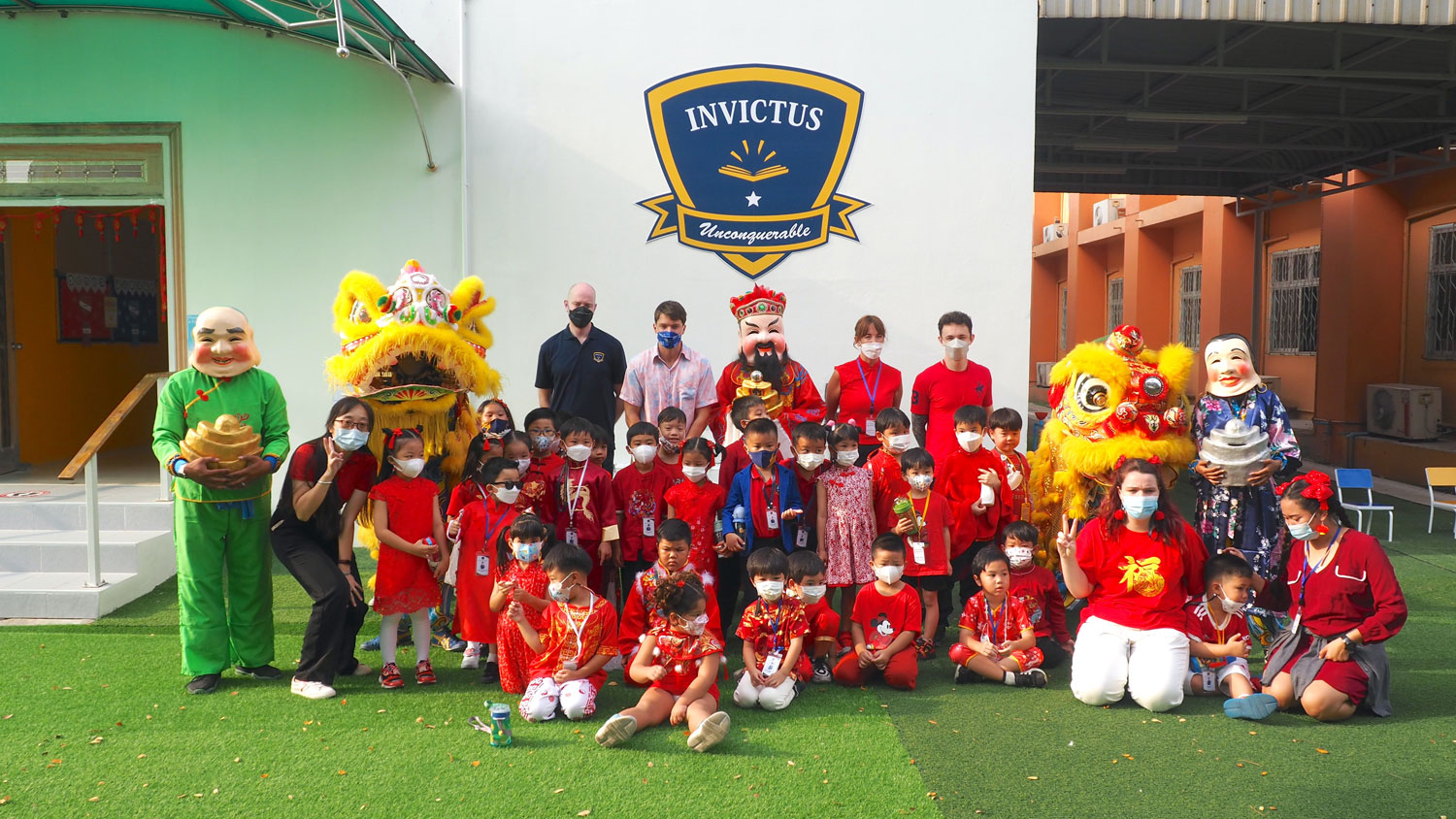 Students and teachers standing in front of Invictus Pathum Thani's logo