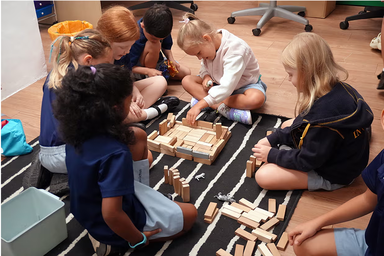 Primary students developing teamwork and problem-solving skills through hands-on block play in a collaborative classroom environment.