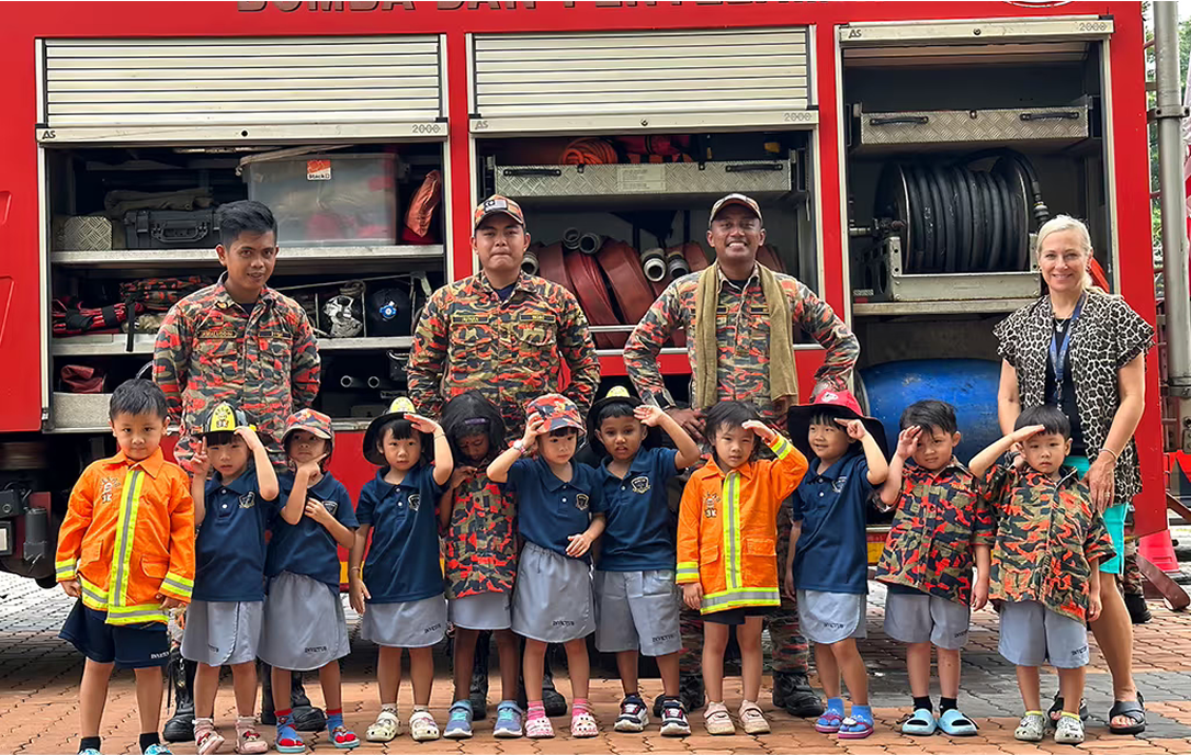 Early years students at Invictus Spring Hills posing with local firefighters during an engaging fire safety learning experience on campus.