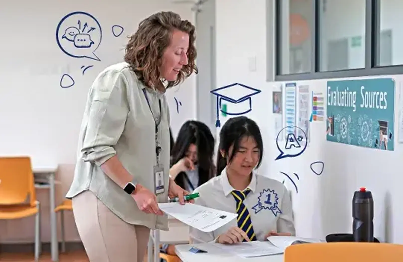 A teacher supports a secondary student during an interactive classroom lesson on evaluating sources, fostering academic confidence at Invictus International School.