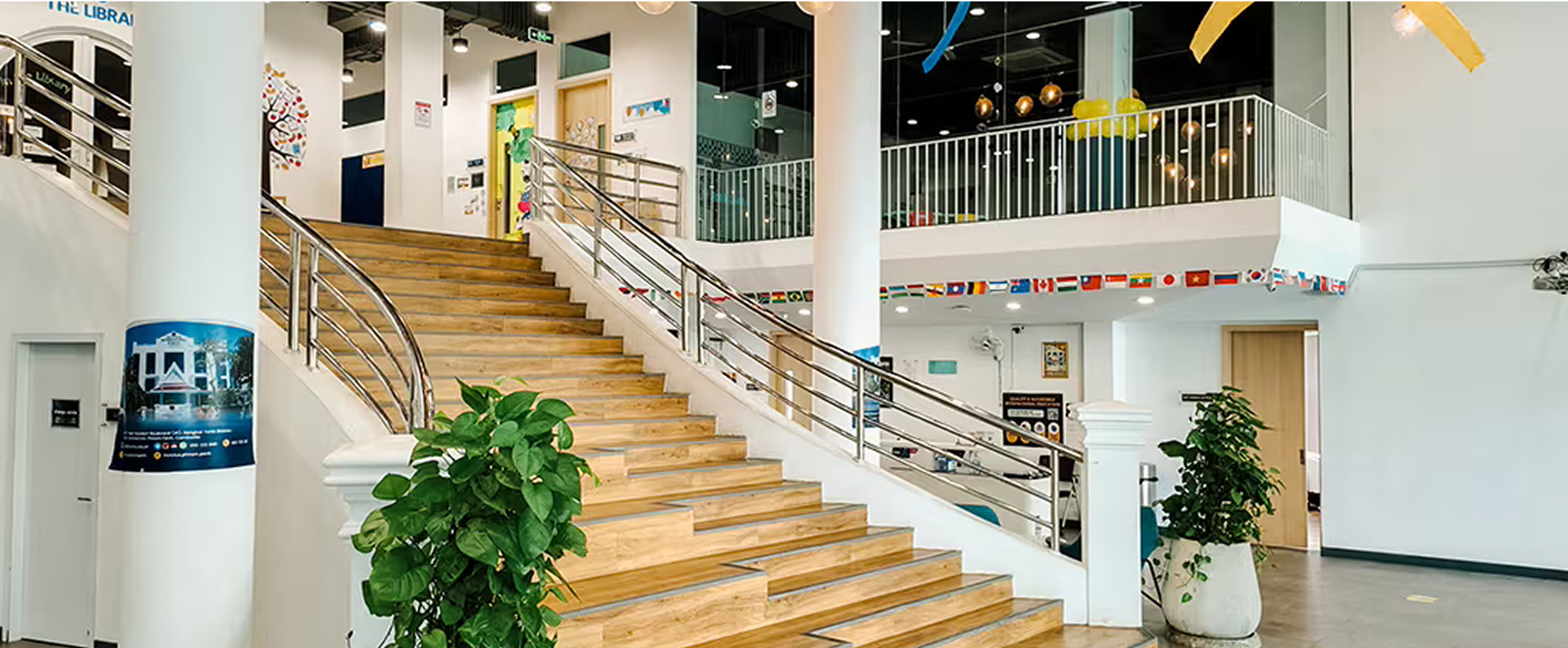 Main staircase and reception area of Invictus Phnom Penh campus, adorned with flags and vibrant decor.