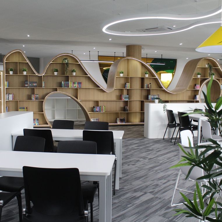 Contemporary library space with unique wave-like shelving and open reading areas at Horizon Hills Invictus International School Malaysia.