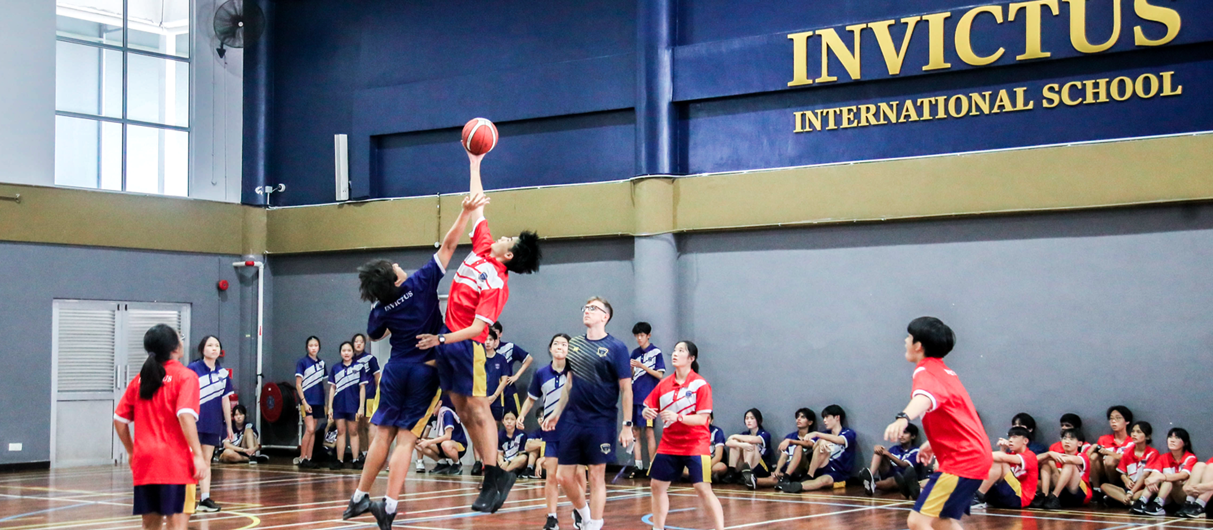 Students dressed in vibrant traditional Chinese outfits perform a cultural dance on stage, celebrating diversity and heritage at Invictus International School.