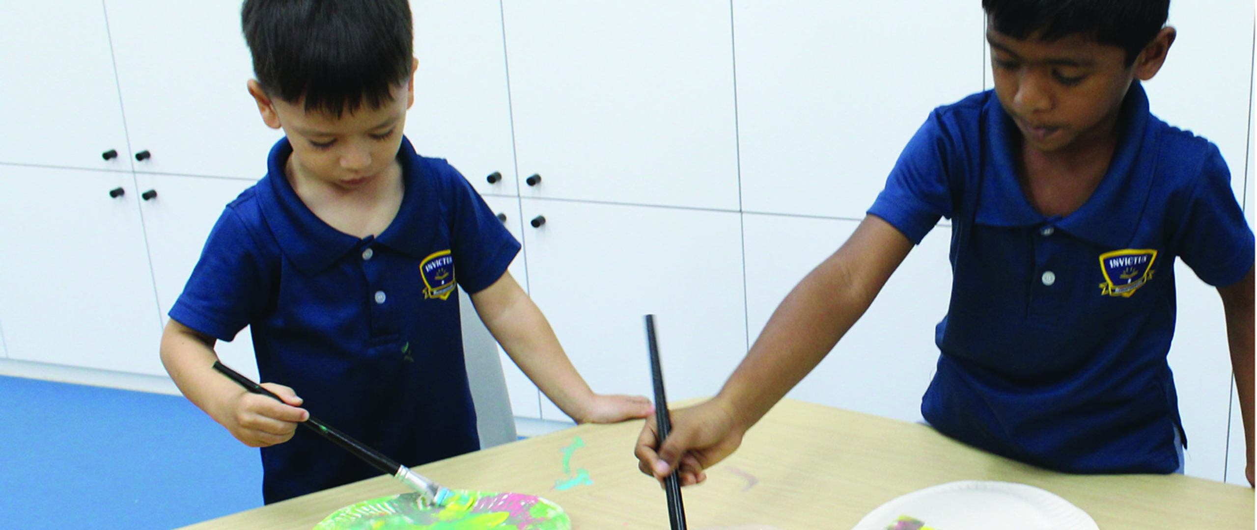 Young students painting with bright colours during an art activity at Horizon Hills Invictus International School Malaysia, expressing creativity through hands-on learning.