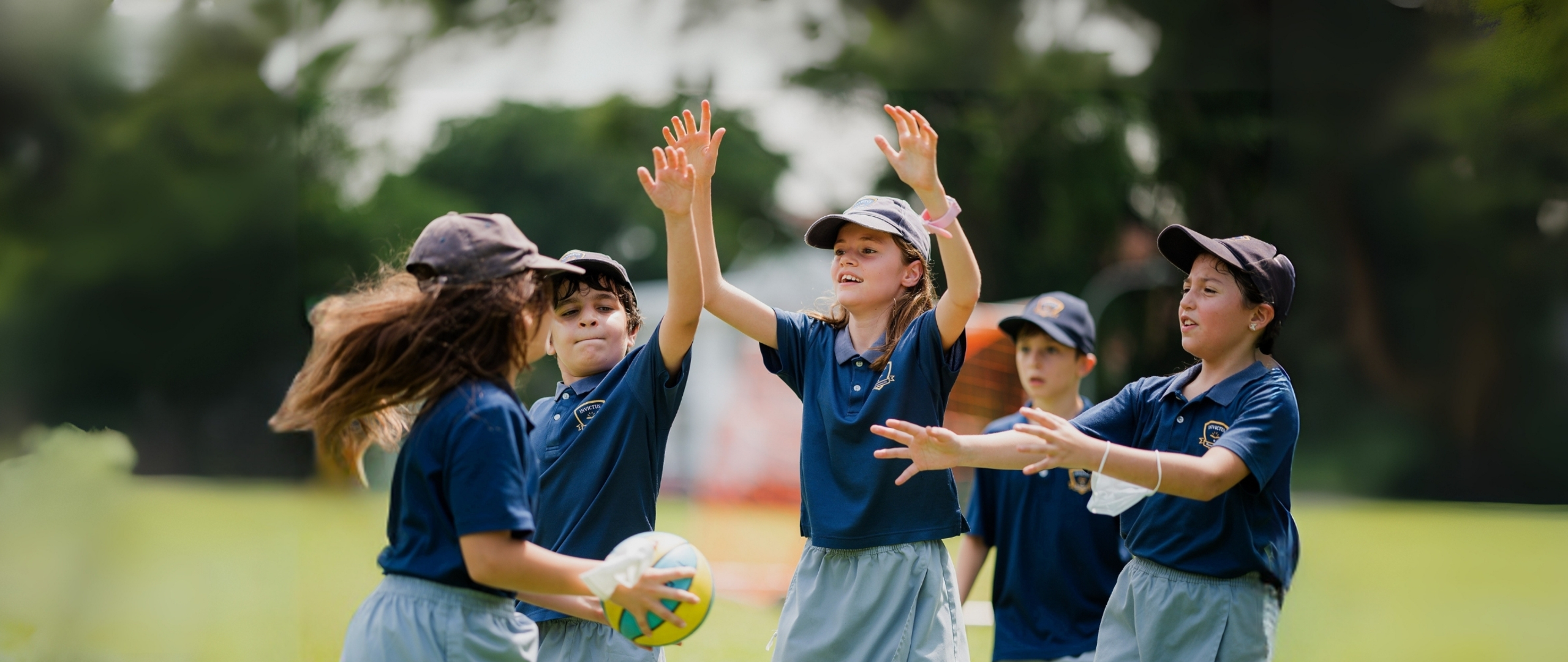 Primary students at Invictus International School Singapore participating in an outdoor sports activity, showcasing teamwork, coordination, and active learning in a lush green field.