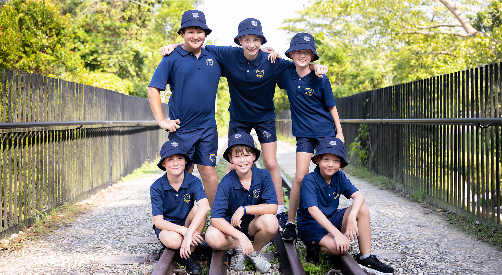Group of Invictus International School Singapore primary students in uniform posing happily outdoors on a nature trail, showcasing school spirit, friendship, and a vibrant learning community.