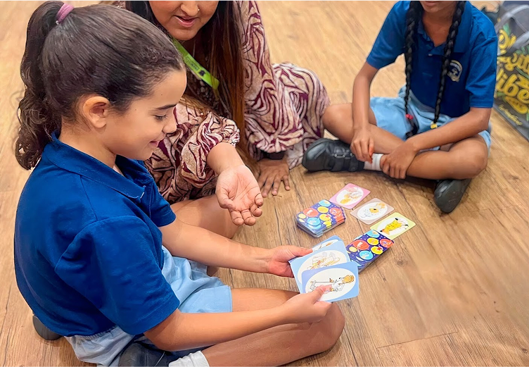 Students engaging in an interactive language or logic card game with a teacher during an after-school ECA at Invictus.