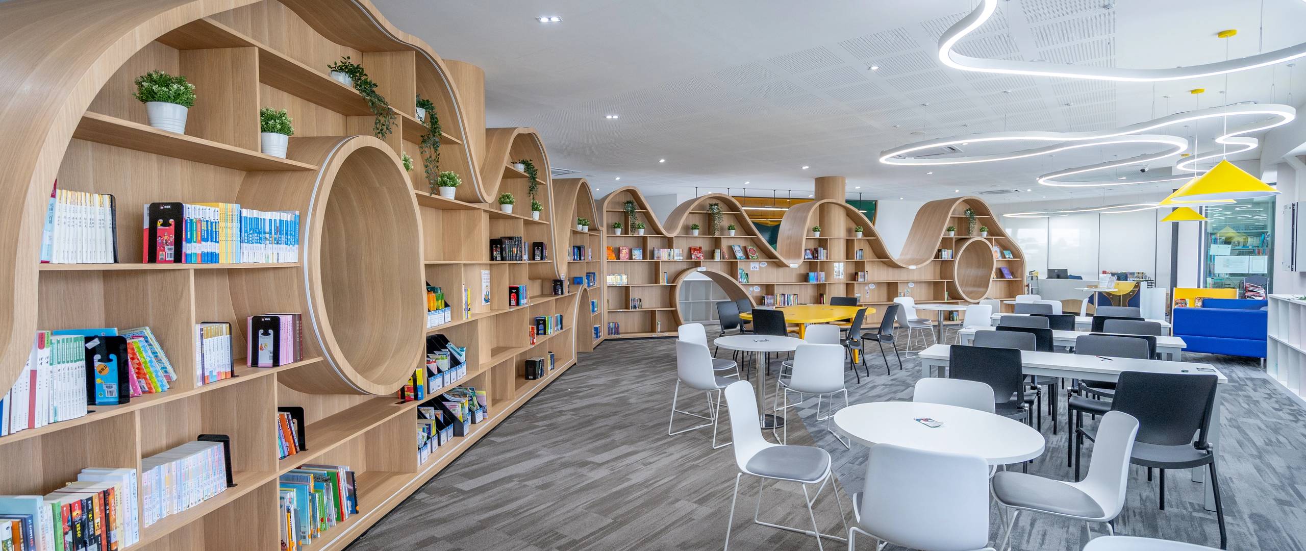 Wide view of learning hub with sculptural shelves and flexible seating.