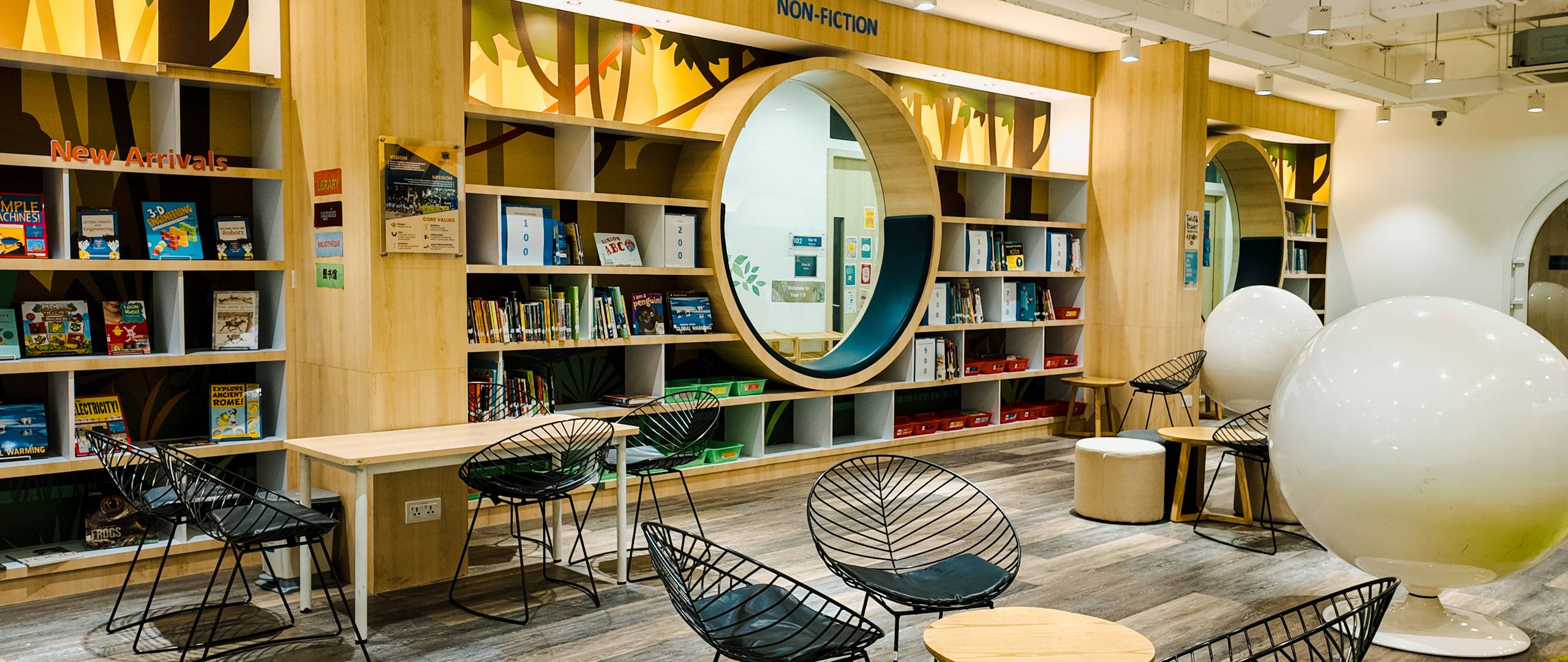 Modern and cosy library space at Invictus International School Phnom Penh featuring circular reading nooks, shelves of books, and comfortable seating.