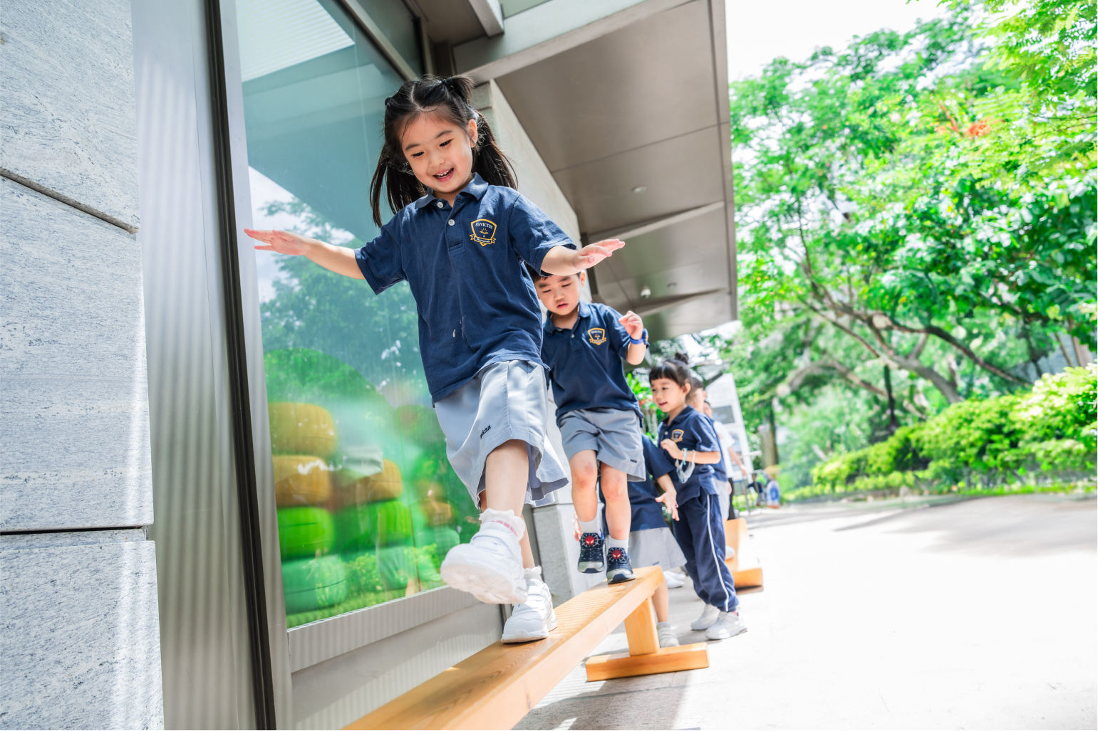 Young students balancing on a beam outside