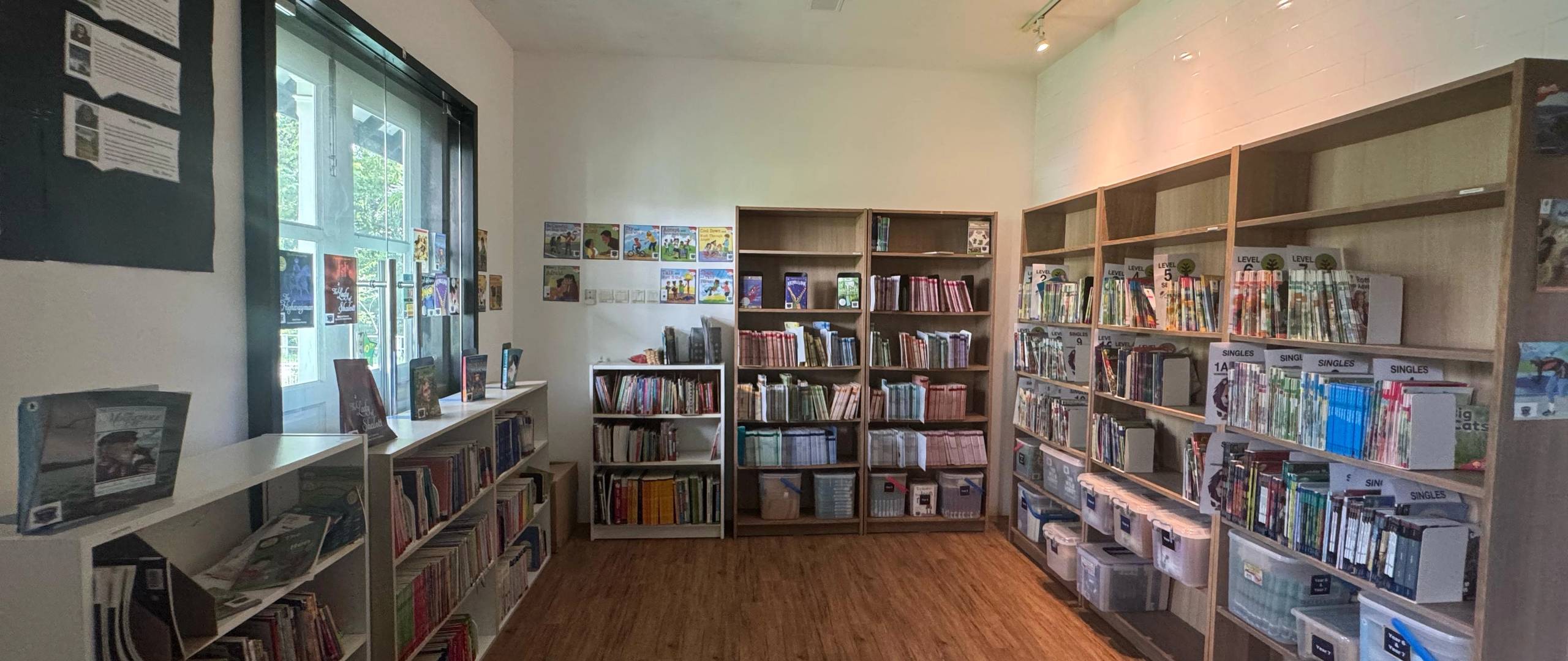School library with wooden bookshelves and children’s reading materials.