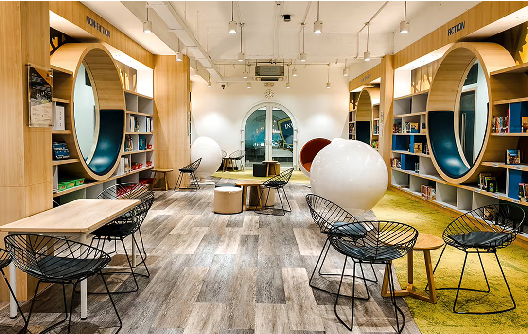 Spacious school library at Invictus Phnom Penh featuring circular reading pods built into the bookshelves, with cosy seating and contemporary furniture creating an inviting learning environment.