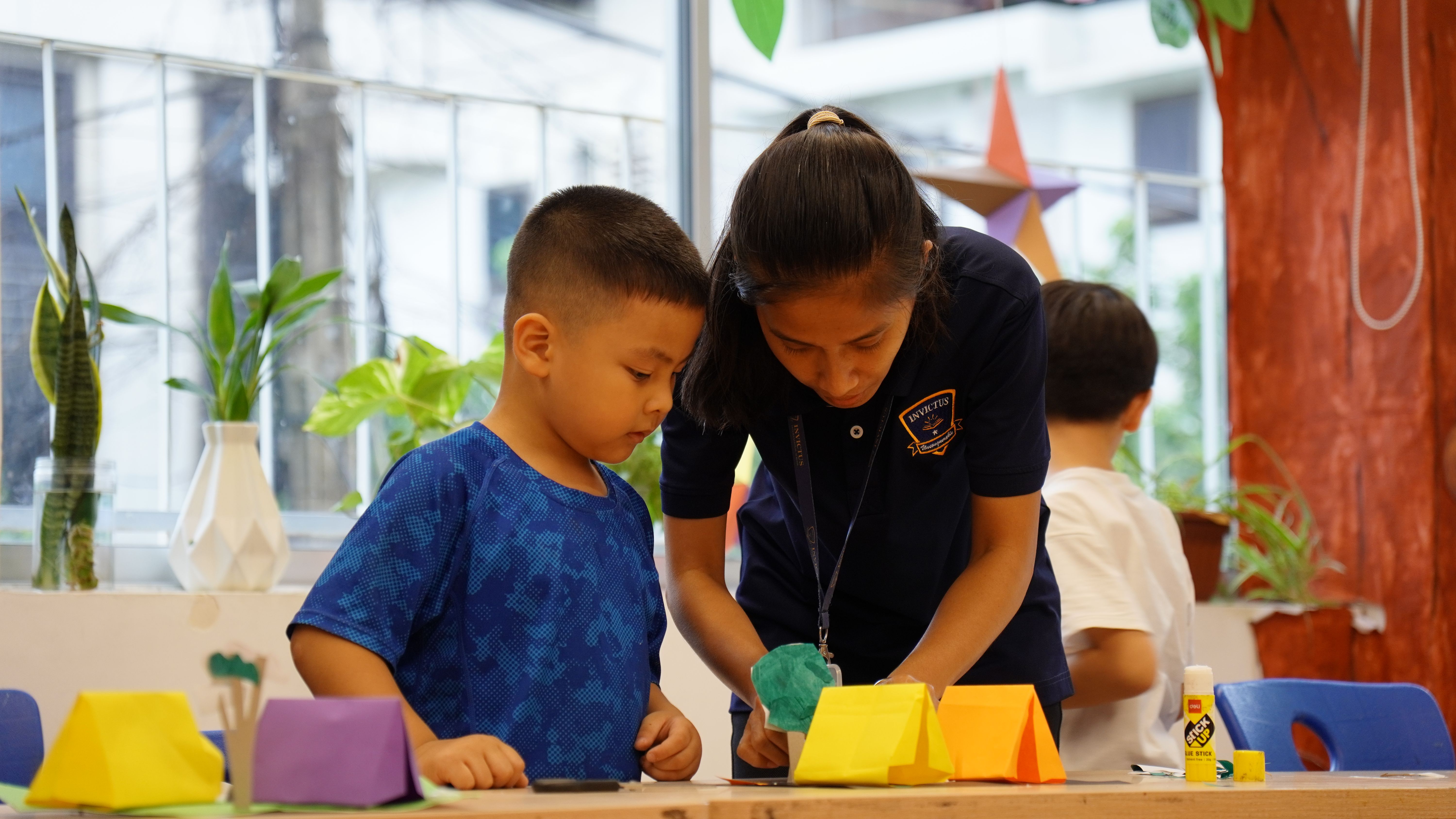 Two secondary students at Invictus Phnom Penh playing badminton indoors during a PE session.