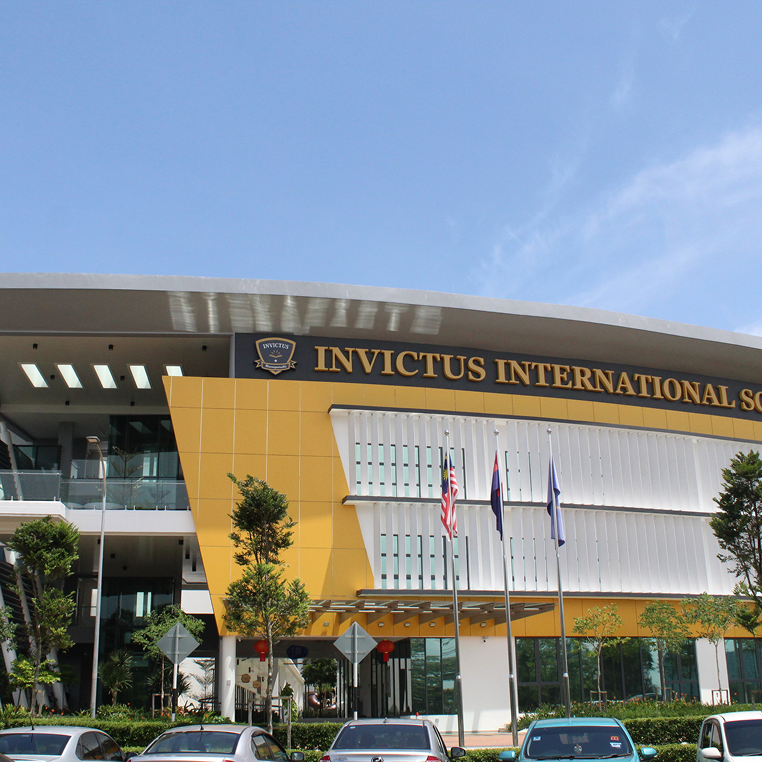 Main façade of Horizon Hills Invictus International School Malaysia with school name signage and national flags displayed.