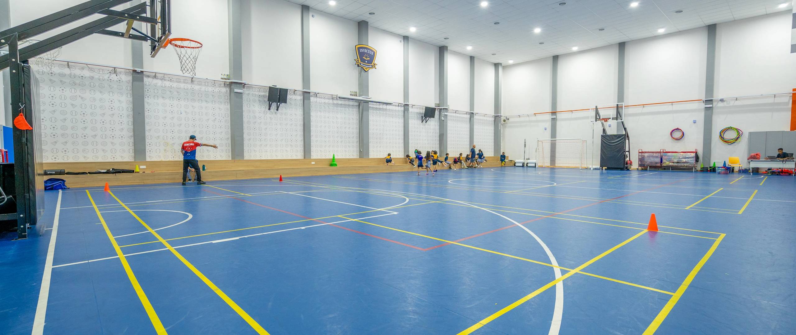Indoor sports hall with basketball hoops and PE setup.