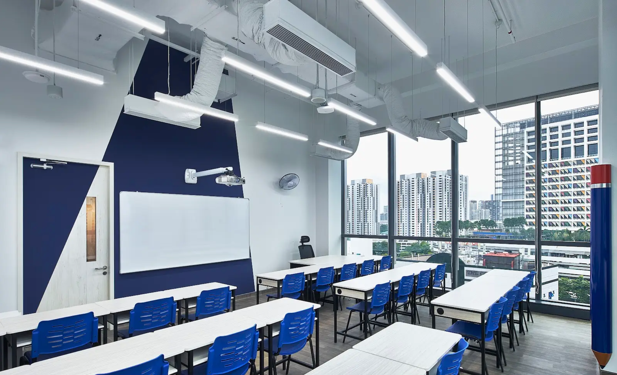 The Invictus International Programme signboard in navy and gold mounted on the Monterey Place campus façade, surrounded by greenery.