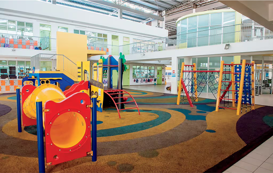 Colourful early years playground at Spring Hills Campus, featuring tunnels, climbing structures, and child-friendly flooring in a bright, open indoor space.
