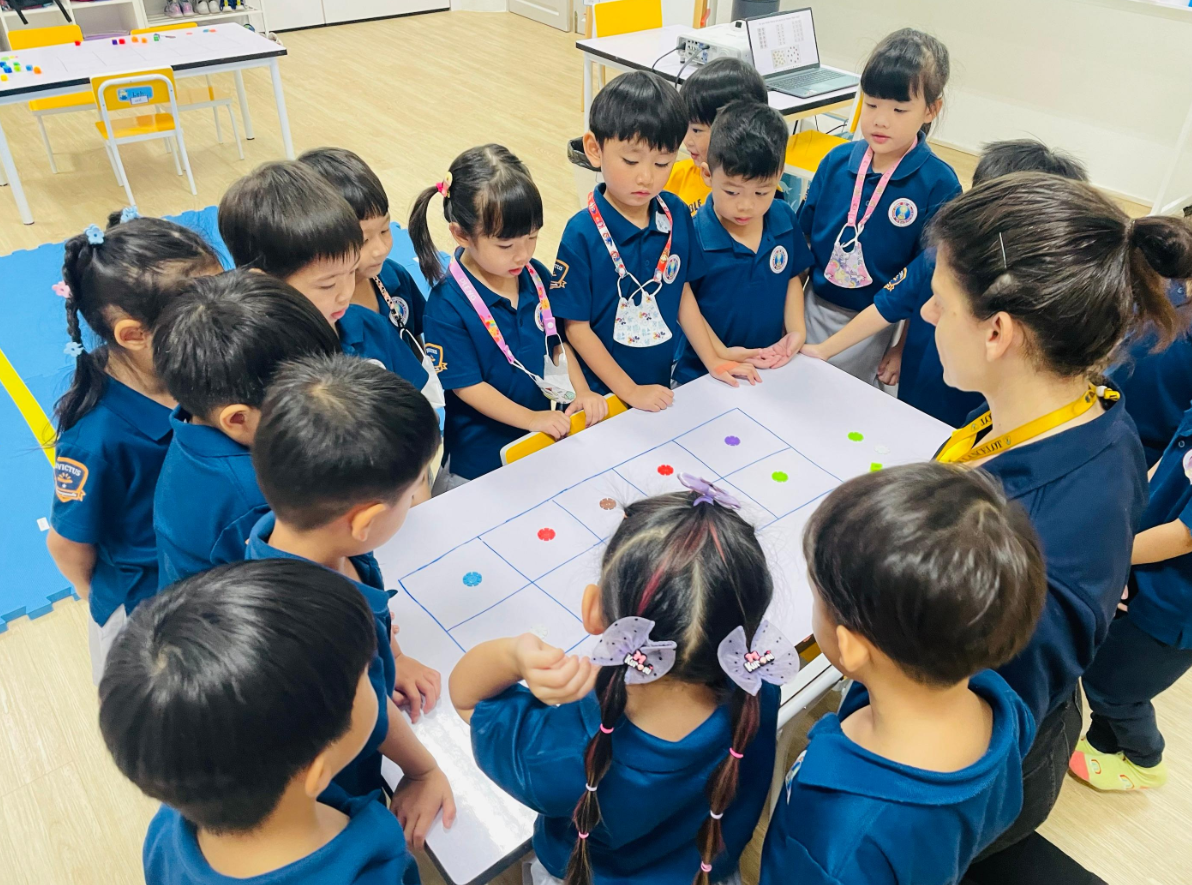 Young students and teachers dressed in red for a Chinese New Year celebration, posing with traditional lion dance performers and festive mascots at Invictus Pathum Thani.