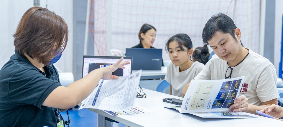 A parent and child engaging with Invictus admissions staff during a campus tour, reviewing a printed school brochure.