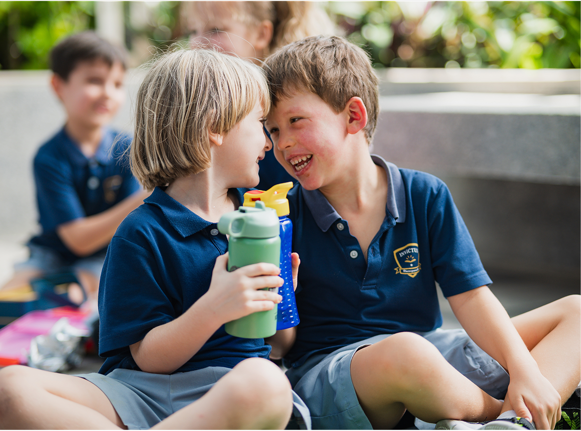 Two boys holding their water bottles and laughing together