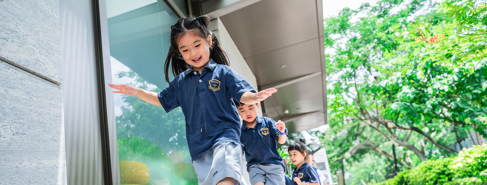 Young student at Invictus International School Hong Kong engaging in playful learning outdoors in school uniform