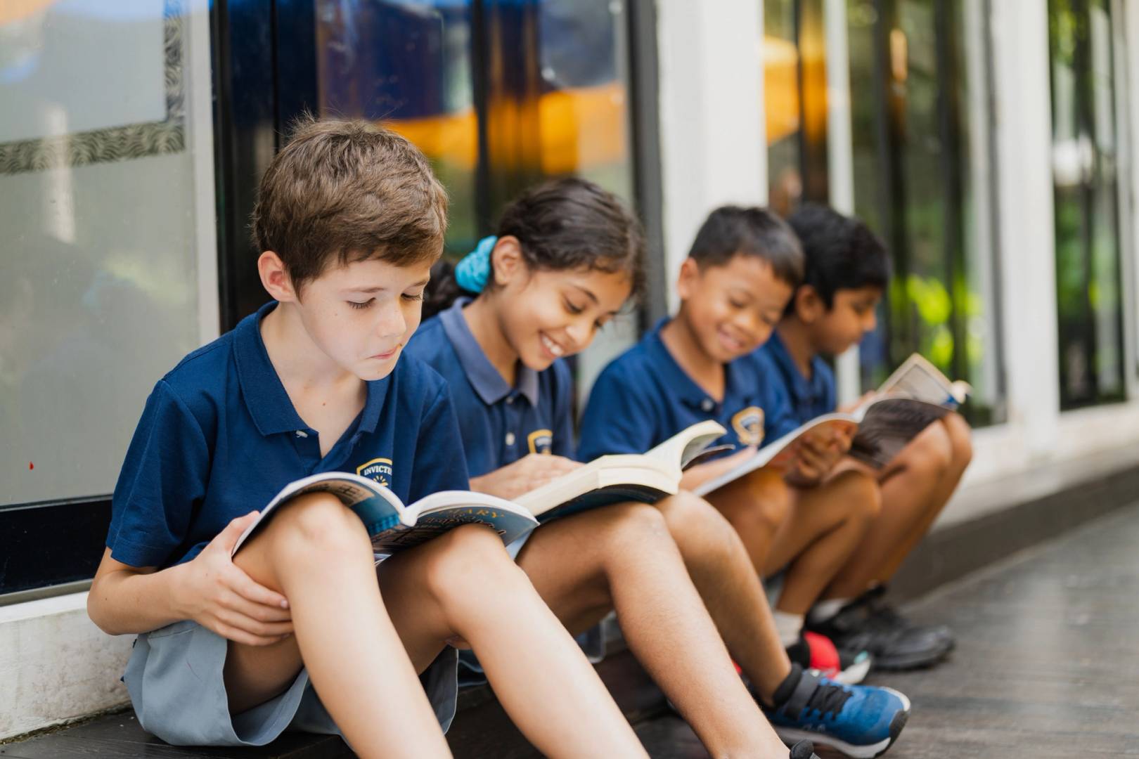 Four students reading textbooks outside