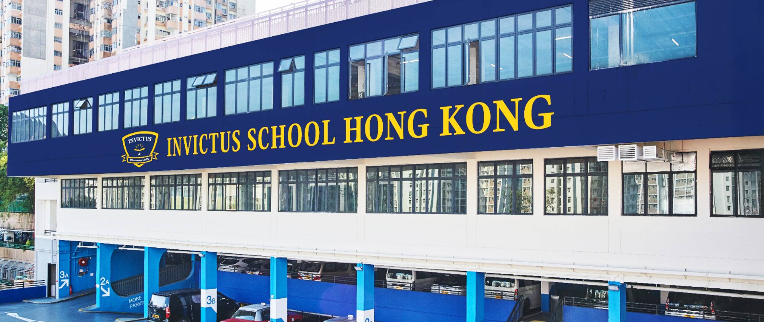 Exterior view of Invictus School Hong Kong building, featuring the school name in bold yellow letters on a navy blue facade above classroom windows.