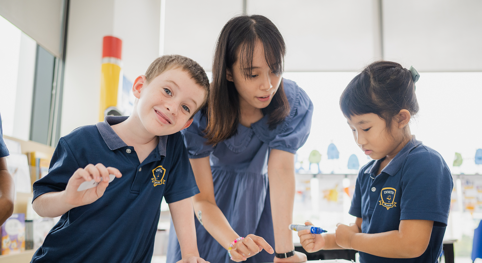 A teacher and two students learning with markers