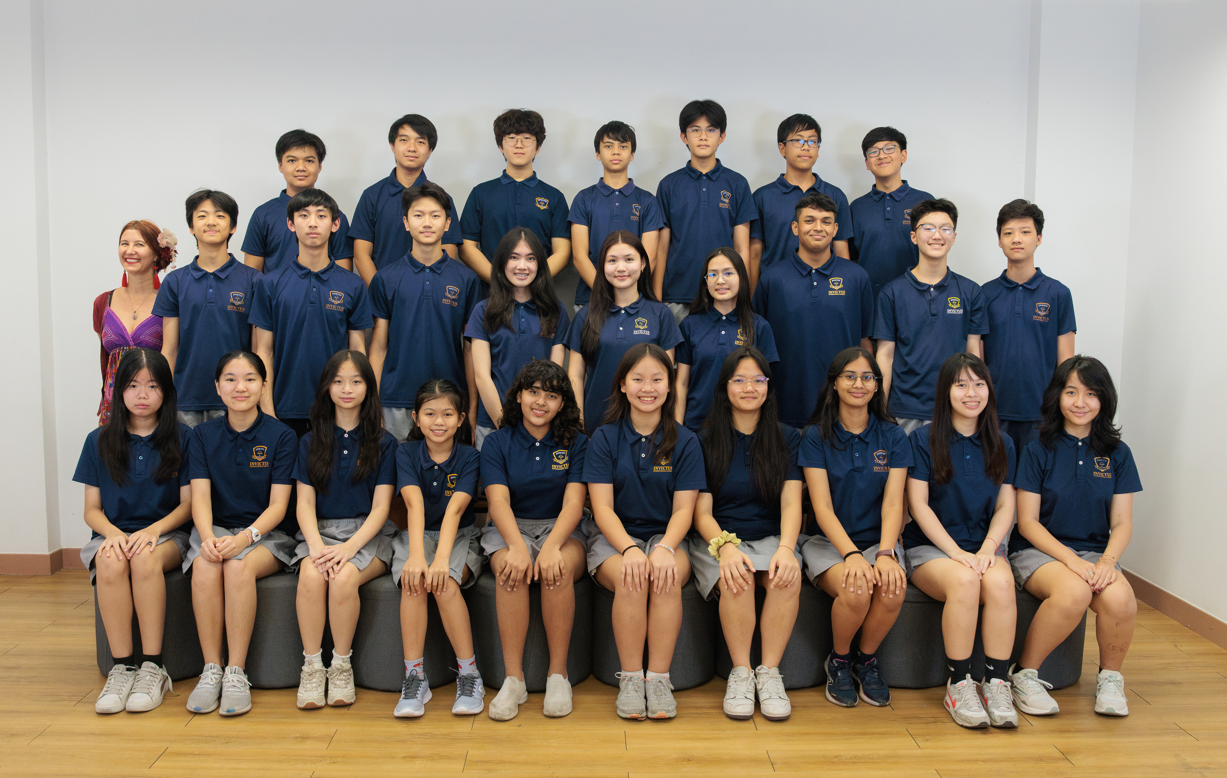 Group photo of Invictus International School Phnom Penh’s student scholars and teacher, all smiling and dressed in navy blue uniforms, celebrating academic excellence and leadership.