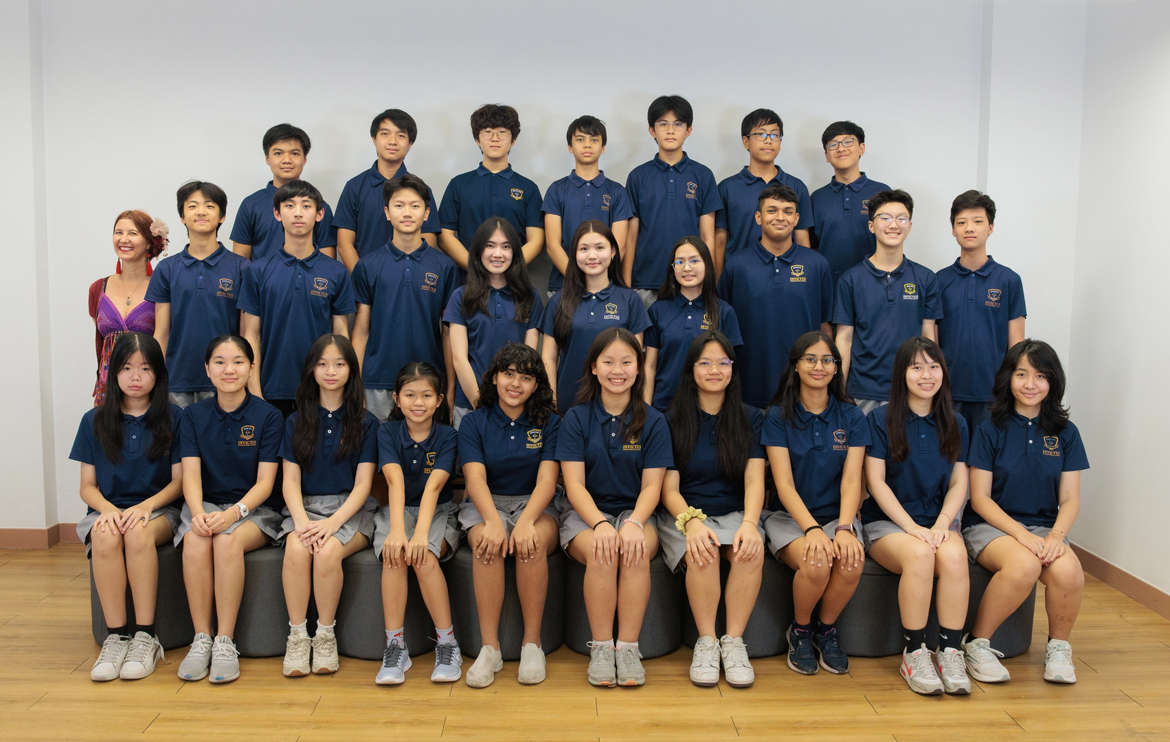 Group photo of Invictus International School Phnom Penh’s student scholars and teacher, all smiling and dressed in navy blue uniforms, celebrating academic excellence and leadership.