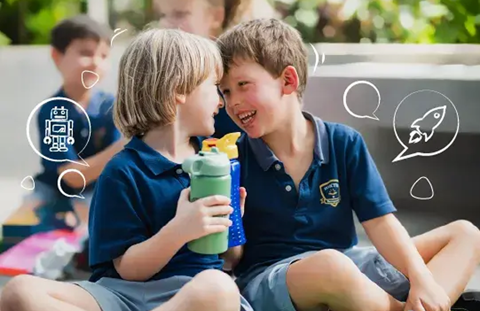 Two young boys share a joyful moment while seated outdoors, chatting and laughing during break time at Invictus International School.