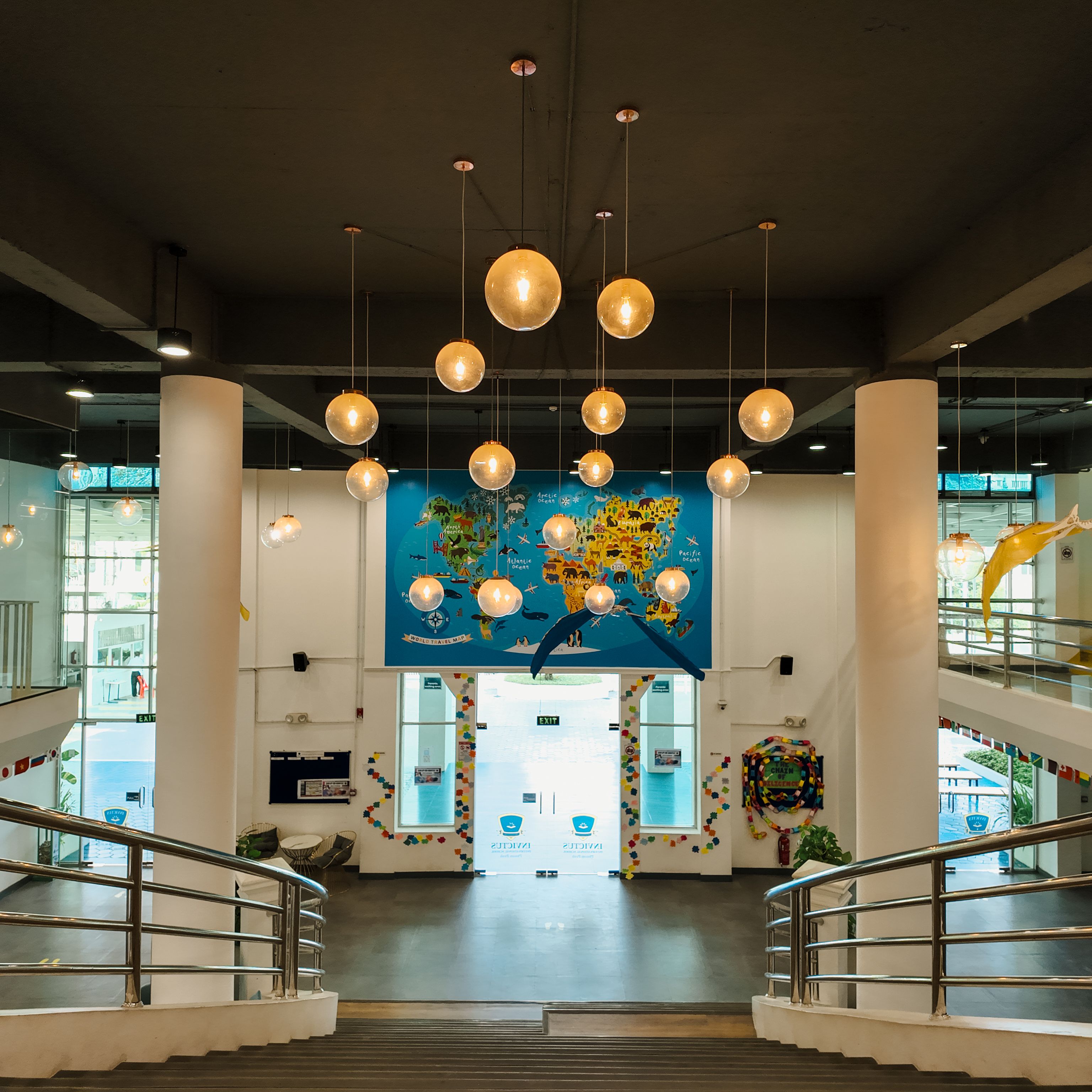 Main staircase and reception area of Invictus Phnom Penh campus, adorned with flags and vibrant decor.