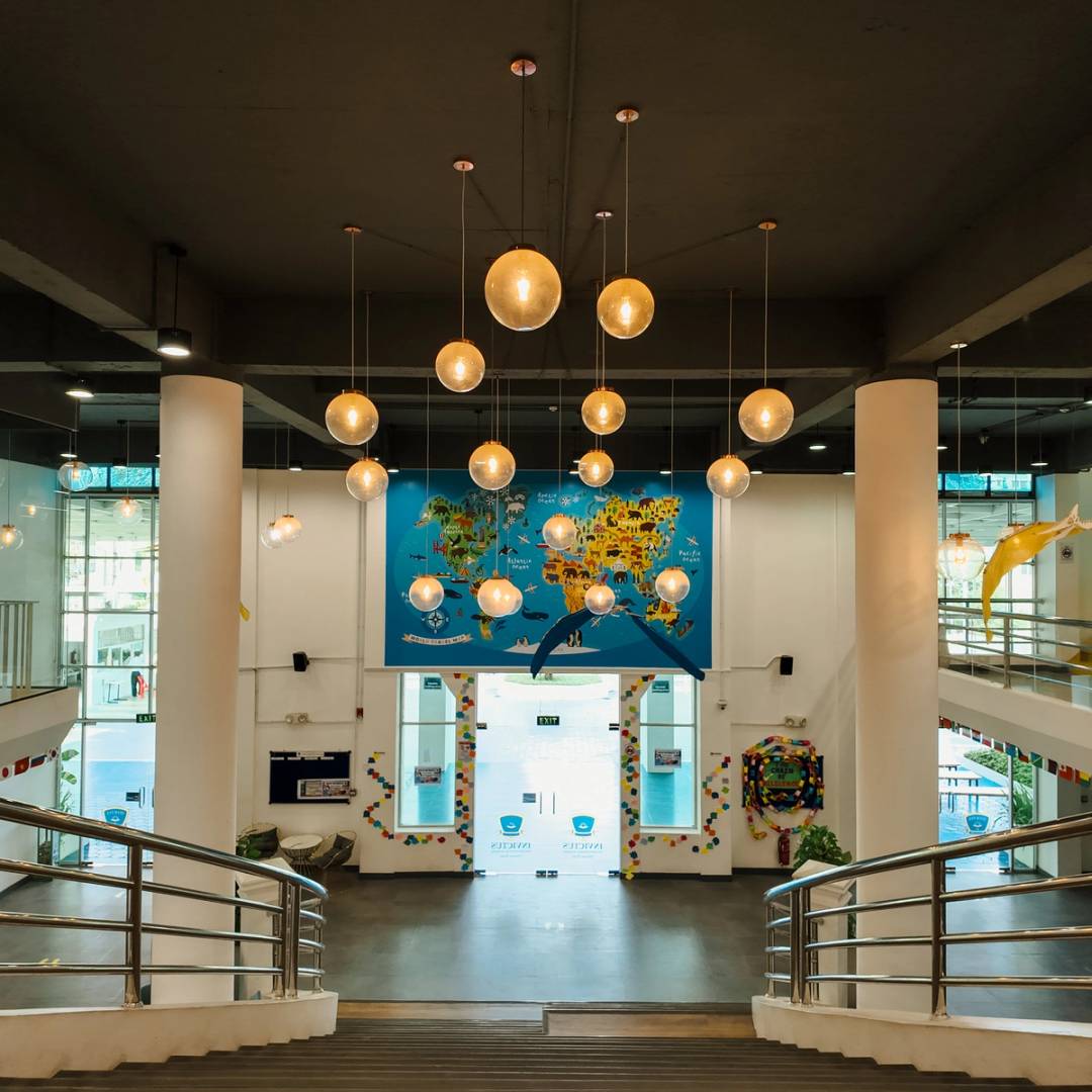 Main staircase and reception area of Invictus Phnom Penh campus, adorned with flags and vibrant decor.