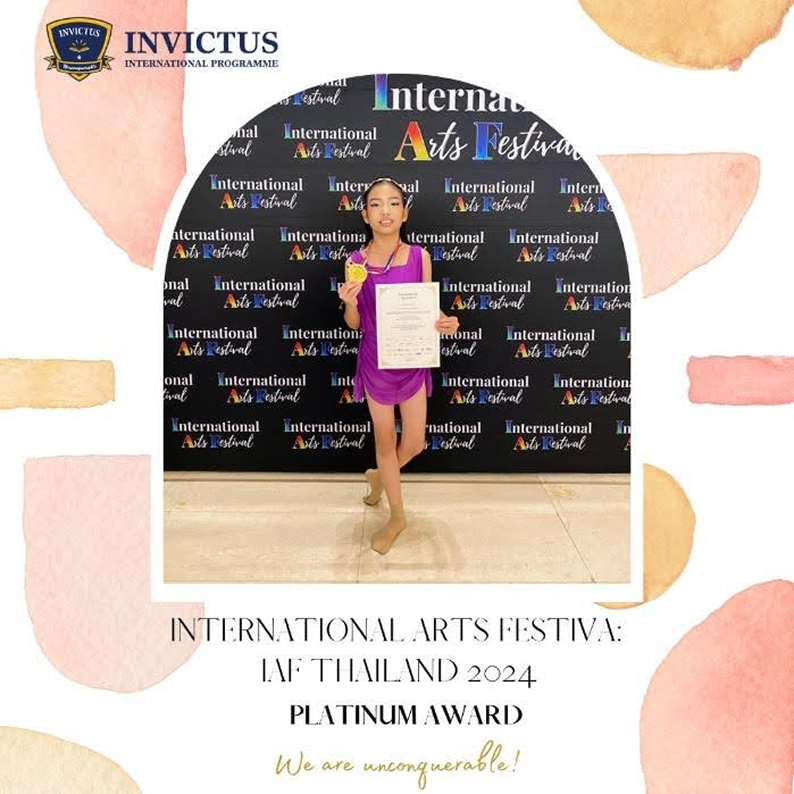A girl in a purple dance outfit smiling with her certificate and medal in front of a backdrop reading “International Arts Festival,” celebrating her Platinum Award at IAF Thailand 2024.
