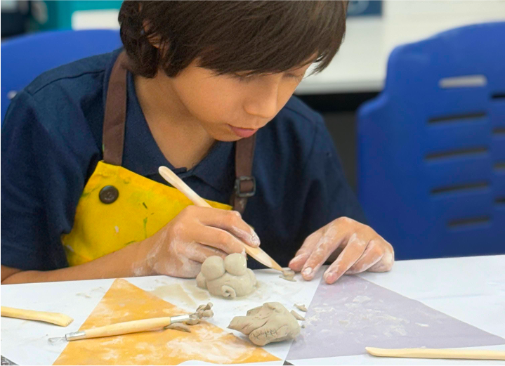 Student shaping clay figures during an arts and crafts ECA, developing fine motor skills and creativity at Invictus.