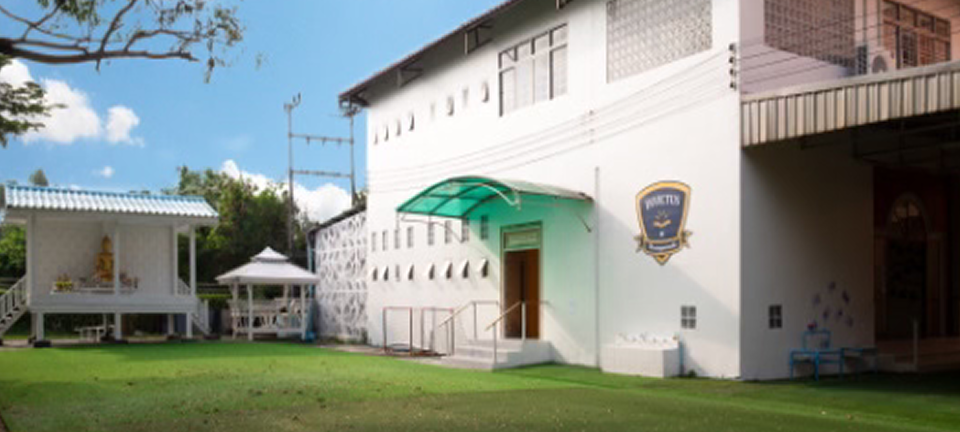 Wide shot of the Invictus International Programme building at Pathum Thani, with a manicured lawn and white pavilion in front of the main entrance.