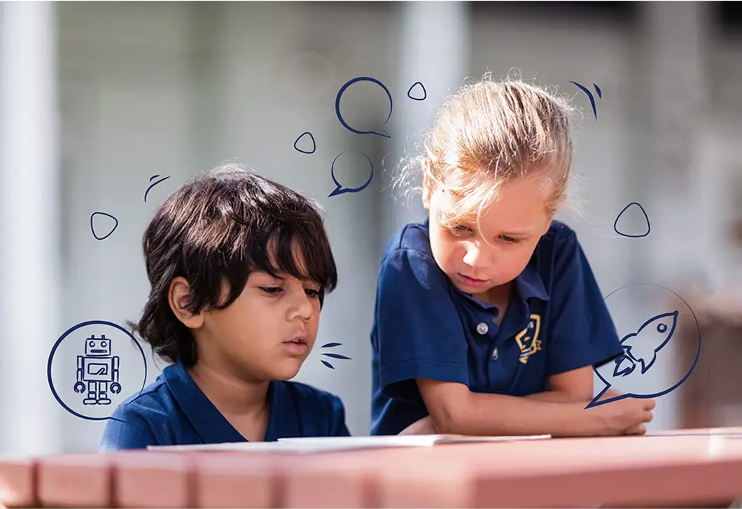 Two young Invictus students reading a book together at an outdoor table, with playful illustrations of a rocket and robot surrounding them.