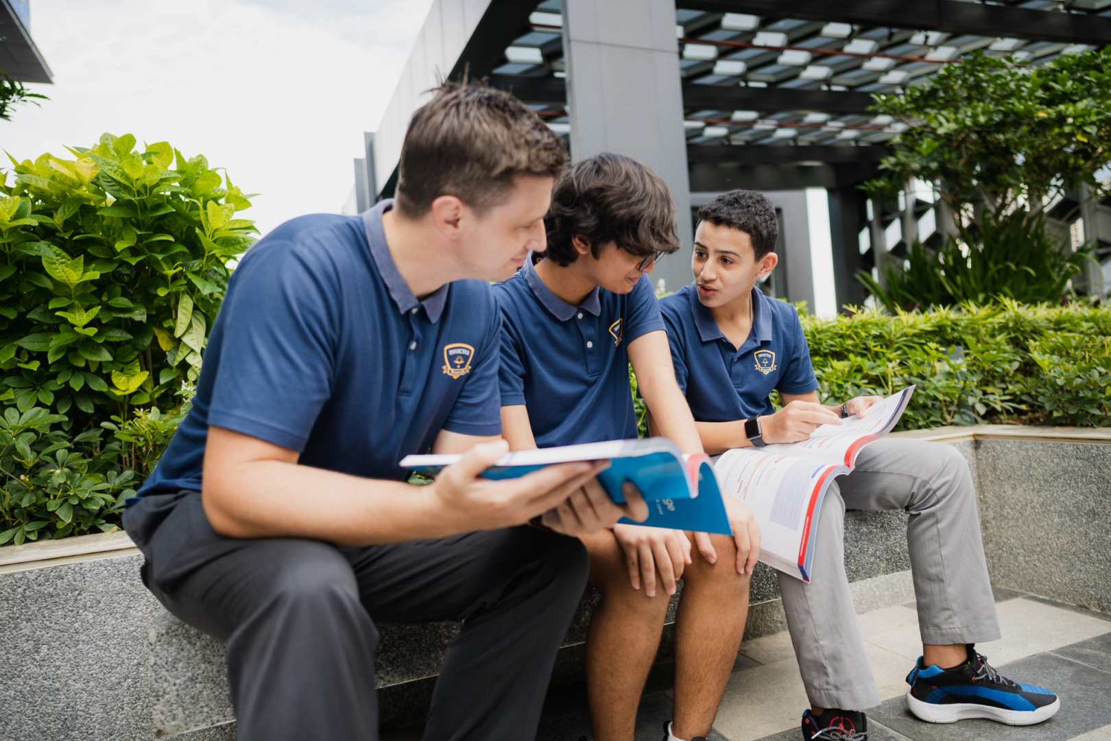 Teacher and two students going over reading materials outdoors